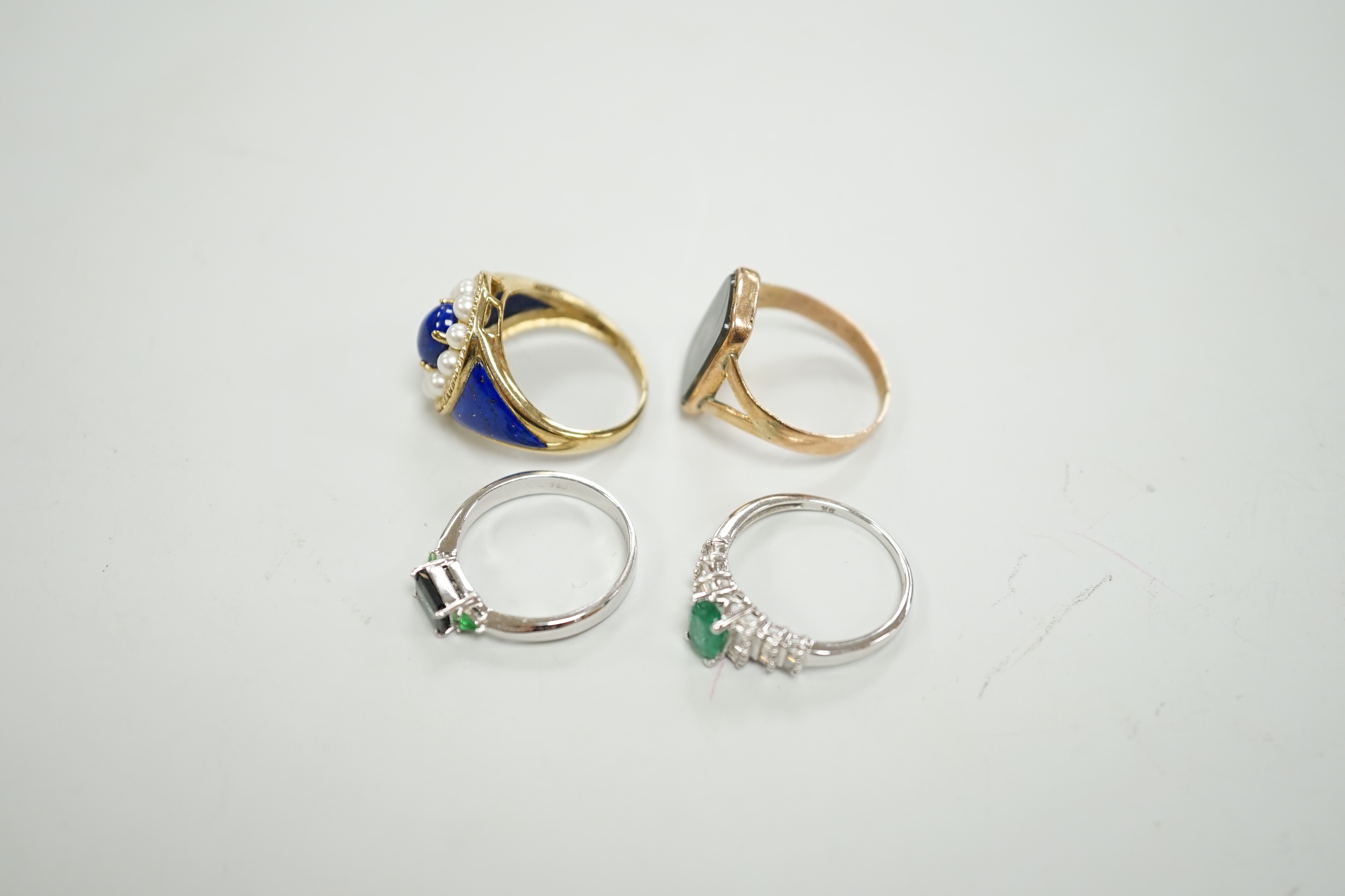 A modern 750 white metal and three stone gem set ring, two 9ct gold and gem set rings including lapis and seed pearl and one other yellow metal ring.